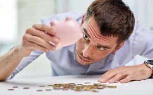 Finanzkrise, Mann mit Sparschwein kaputt, Geld auf Tisch